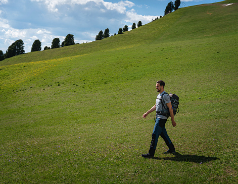 Caucasian man hiking through valley under Alpe di Seceda