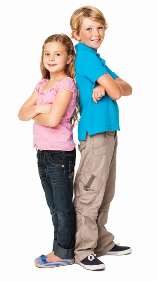 Full length portrait of siblings smiling while standing back to back. Vertical shot. Isolated on white.