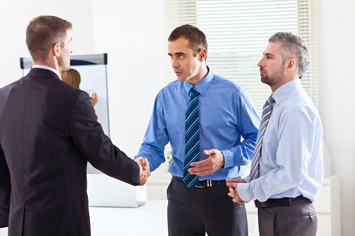 Handsome young businessman shaking hands with business partners.