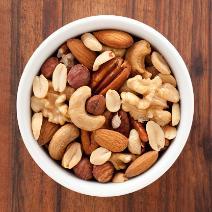 Top view of white bowl full of variety of nuts