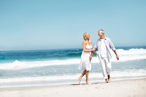 Full-length image of a healthy senior couple enjoying a carefree walk along the seashore - copyspace