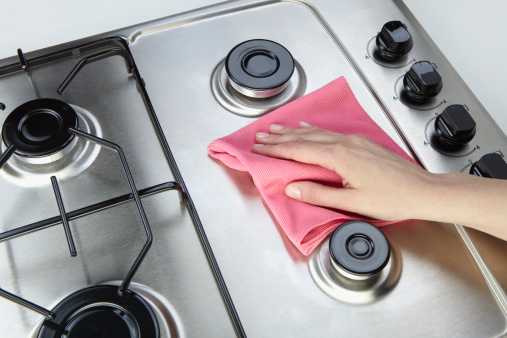The woman cleaning set-top stove with rag