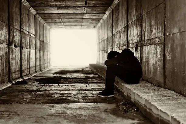 Boy sat in a corridor with the head covered