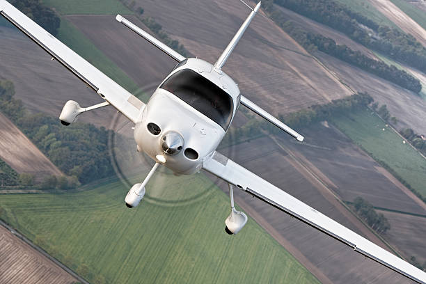 Airtoair modern civil airplane Air to air photo of a modern civil cirrus airplane with propeller flying over the agricultural fields, landing gears down. cirrus stock pictures, royalty-free photos & images