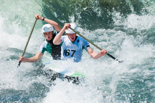 Front view of two young male canoeists in whitewater mist