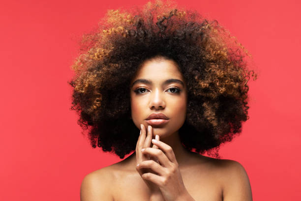 Portrait of Young African model with a beautiful makeup Young beautiful african american woman with afro hair. Red Background. teenage girl before and after make up stock pictures, royalty-free photos & images