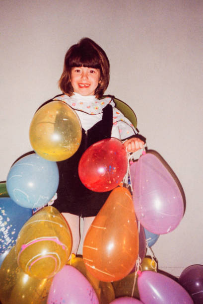 Vintage portrait of cheerful girl during birthday with balloons in 90's in Brazil stock photo
