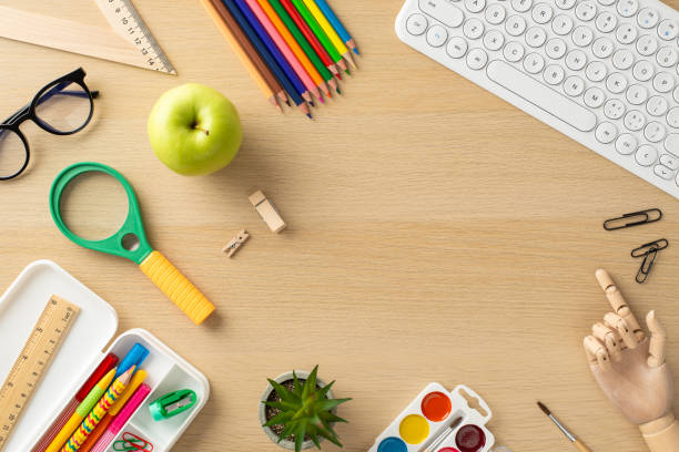 istock Engage in remote learning with this creative top-view shot, showcasing a keyboard, pencil case and glasses on wooden background. Utilize the available space for text or promotional messages 1554245281