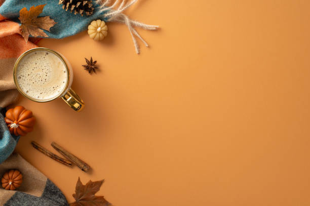 istock Dive into autumn atmosphere. Top-view perspective of cup filled with rich coffee, comfortable plaid, small pumpkins, golden maple leaves, cone, cinnamon, anise, orange backdrop. Empty space for promo 1554246352