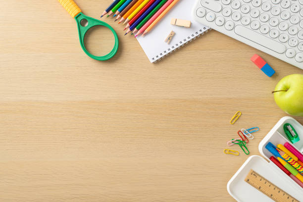 istock Convenience of studying online from home through this top-view image, highlighting keypad, notebook, colorful pencils and stationery on wooden isolated background. Space available for text or adverts 1554259798
