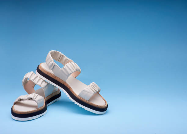 istock A shot of new pastel leather sandals with three-colored soles placed one on another. Gradient blue background. Concept of selling shoes 1554268287