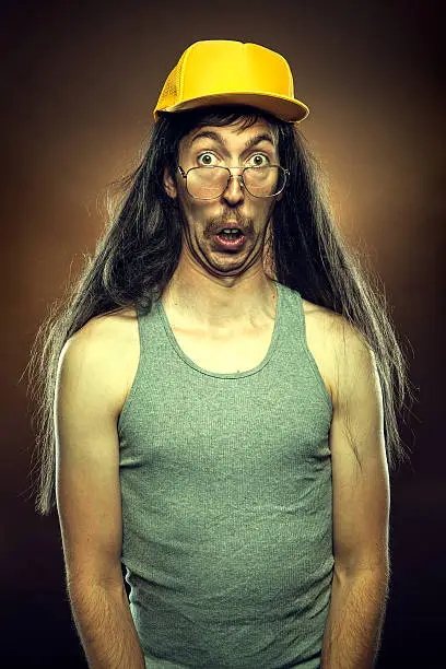 A hillbilly man with a long flowing mullet, mustache, trucker hat,  and rotten teeth looks shocked or surprised at something.   Brown background; vertical.