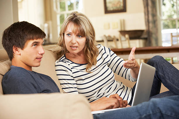 madre e figlio adolescente litigare sul divano - teenager laptop computer anger foto e immagini stock