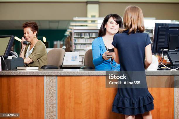 Jovem Verificar Um Livro Da Biblioteca - Fotografias de stock e mais imagens de Bibliotecário - Bibliotecário, Biblioteca, Balcão de Pagamento