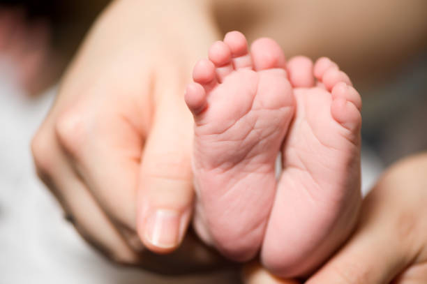 istock Baby's feet and mother's hands 155428878