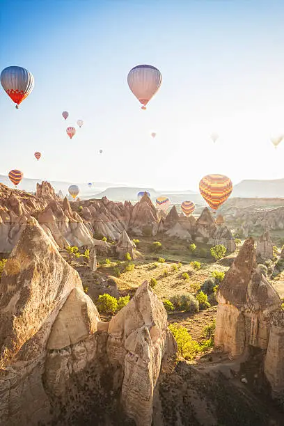 Hot air ballons over Love Valley near Goreme and Nevsehir in the center of Cappadocia, Turkey (region of Anatolia). This shot taken shortly after sunrise shooting into the sun. Sun flares visible.