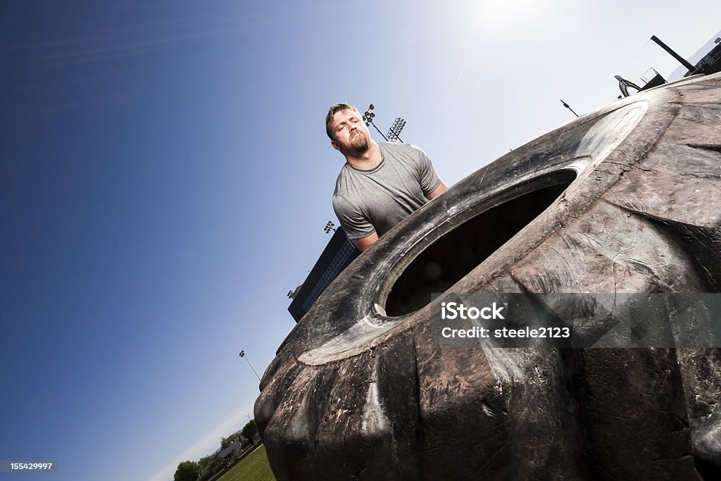 gym Series A muscular man participating in a gym workout by doing a tire flip Active Lifestyle Stock Photo