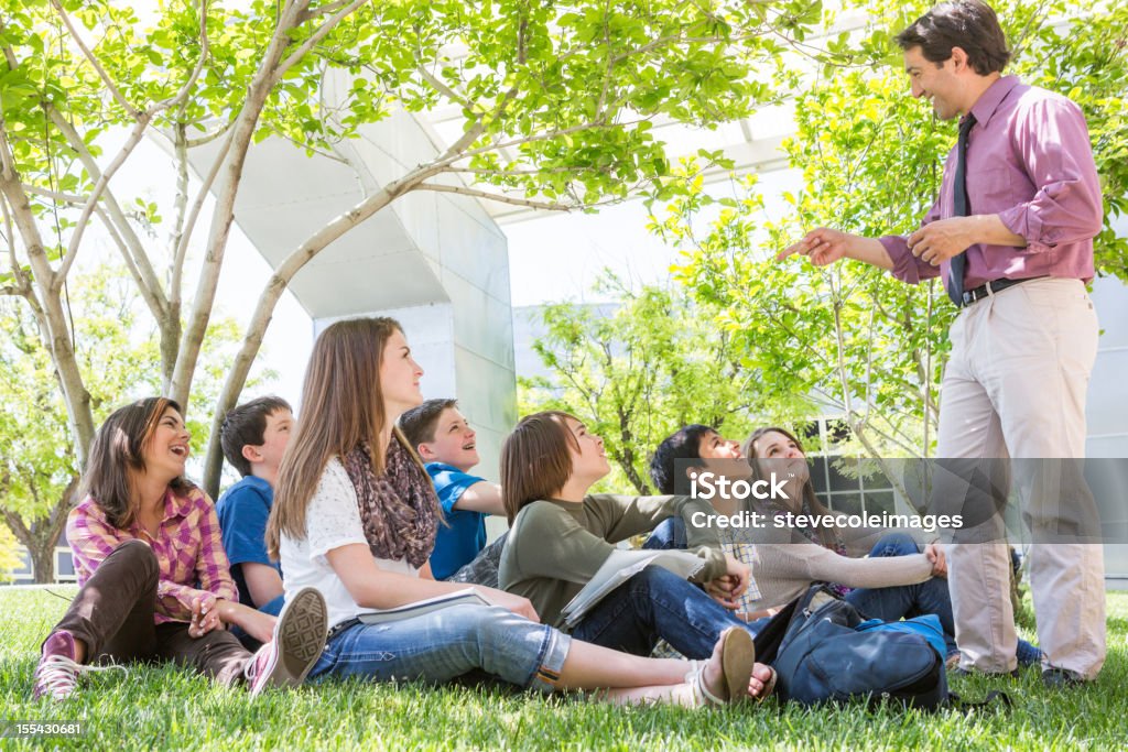 Students in Class Outdoors A teacher teaches middle school students outdoors. Classroom Stock Photo