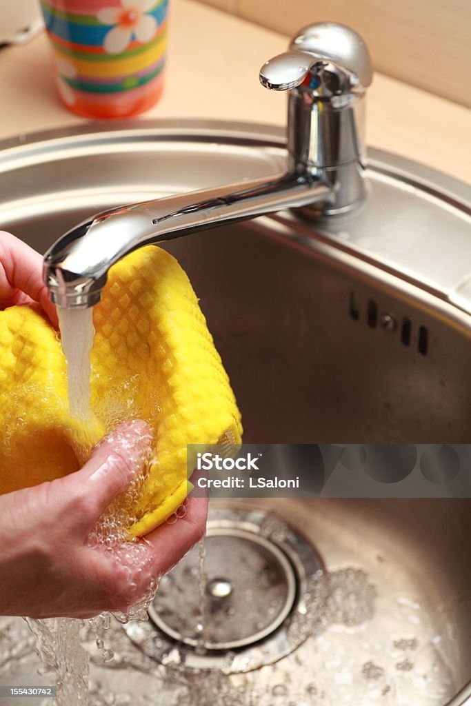 cloth under running water yellow cloth and hands under running water Bathroom Stock Photo