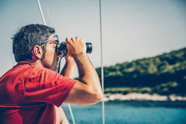 istock Sailor with binoculars on sailboat 1554308285