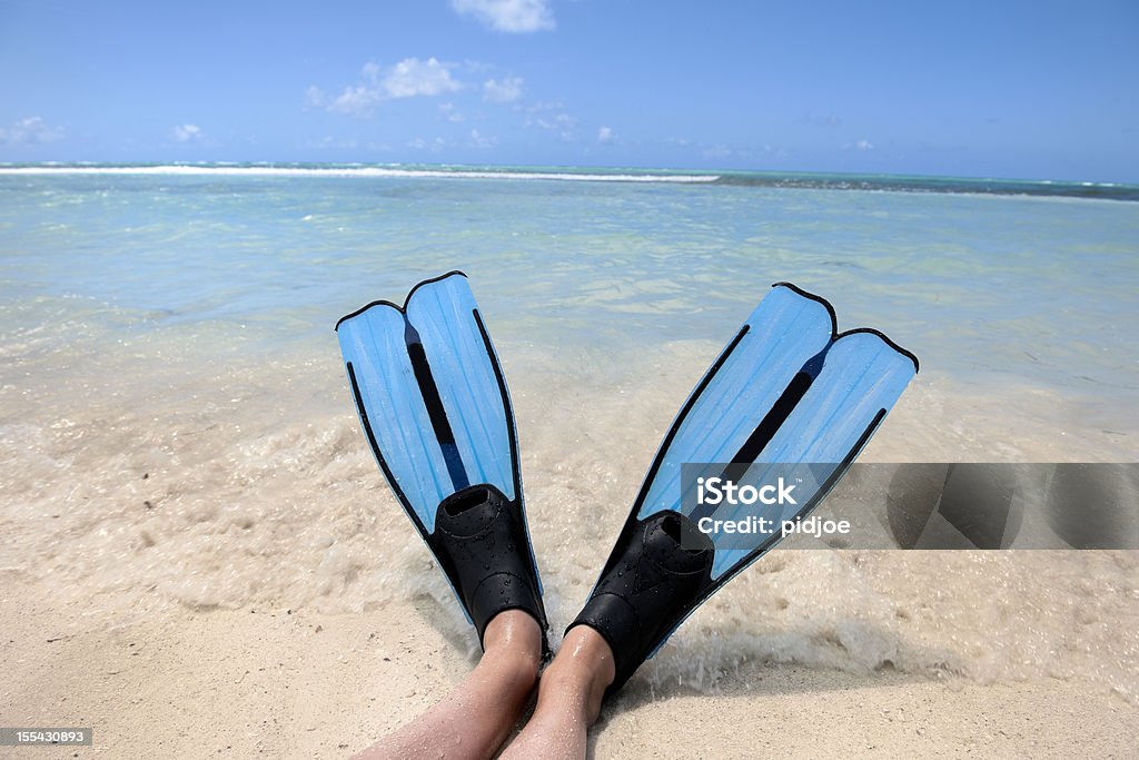 diving flippers on tropical beach close up on feet with diving flippers on tropical beach in the surf on a sunny summer day Beach Stock Photo