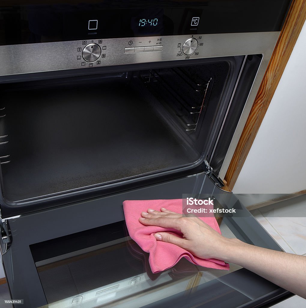 Cleaning oven Woman cleaning oven using microfiber rag. Oven Stock Photo