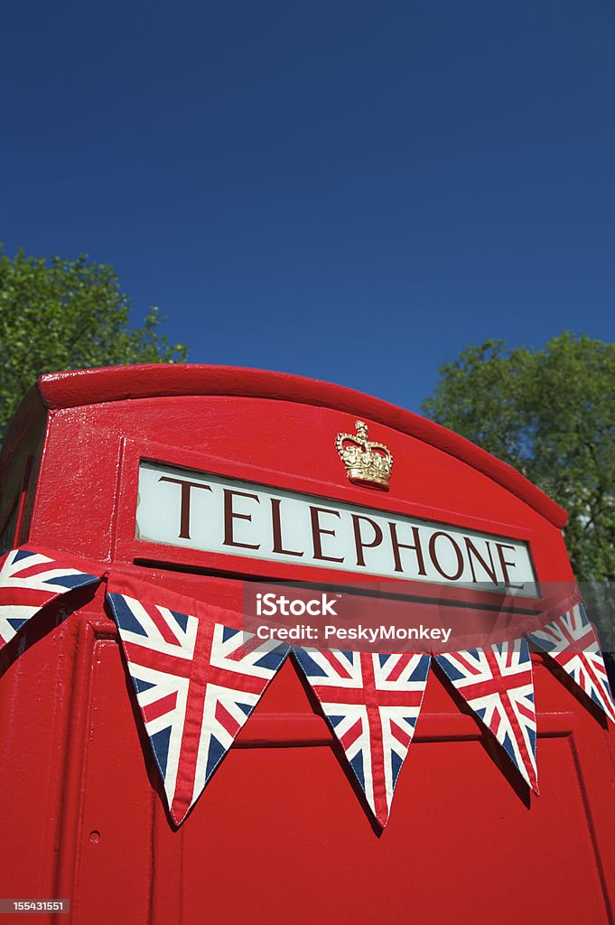 Red Telephone Booth with Union Jack British Flag Bunting Union Jack British Flag bunting hangs across traditional bright red British telephone box  2012 Stock Photo