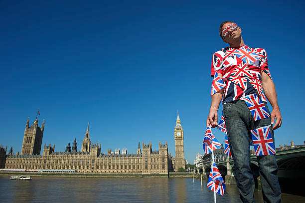 istock Man Stands Tangled in Union Jack Flags London Skyline 155431556