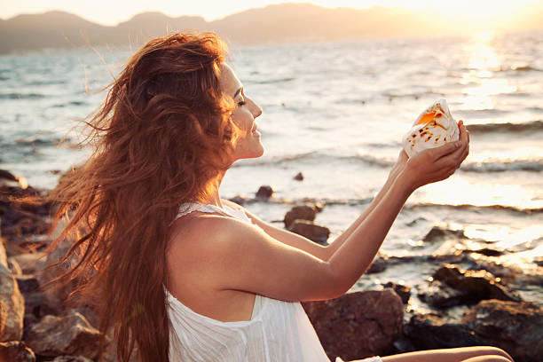 Smiling woman on the beach with seashell