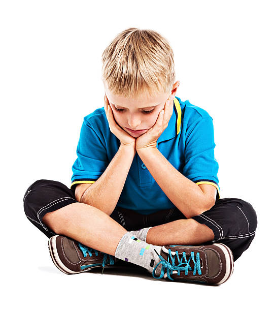istock Depressed-looking little boy sits looking down head in hands 155431830
