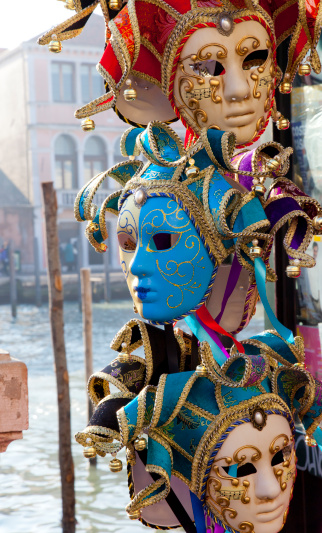 Couple of masks in beautiful purple red costumes on a bridge at carnival in Venice, Italy. Grand Canal and San Giorgio di Maggiore in the background.