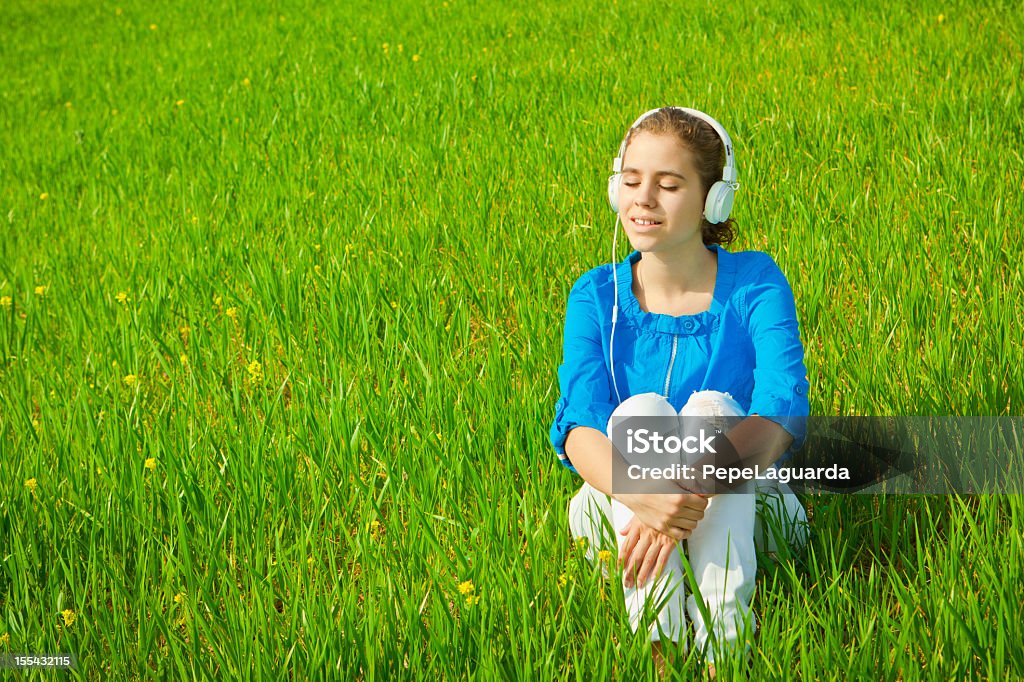 Jeune fille écoute de la musique dans un champ vert - Photo de 14-15 ans libre de droits