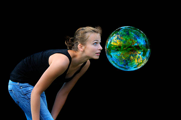 Young happy woman playing with soap bubbles in nature on a sunny summer day.