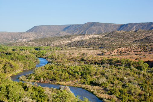the rio chama river flows through a mesa landscape in abiquiu, new mexico at ghost ranch, the famous travel destination of painter georgia o' keefe's retreat while living in new mexico.  horizontal composition.