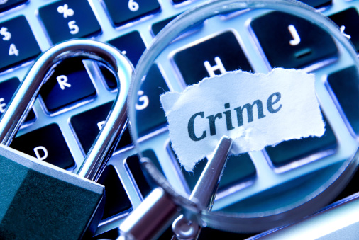 Magnifying the word crime next to a lock on a blue illuminated keyboard