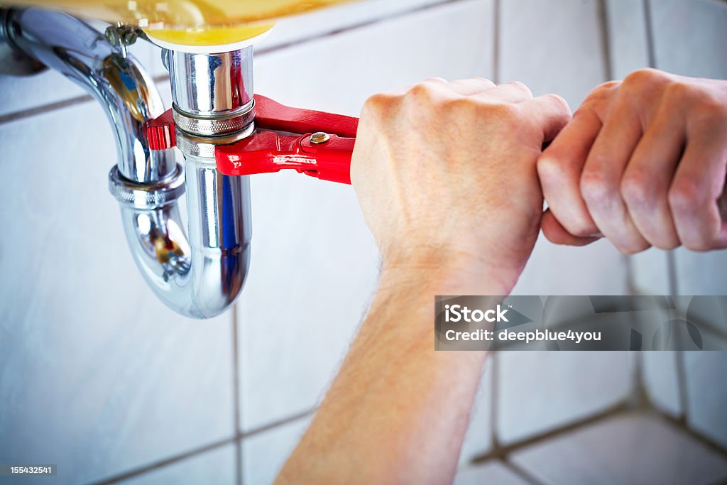 Encanador Mãos segurando a chave e fixação de uma pia de banheiro - Foto de stock de Encanador royalty-free