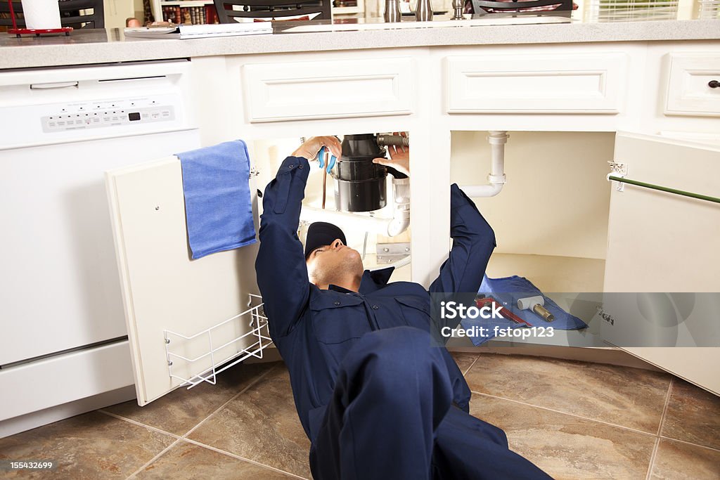 Услуги отрасли: Сантехник, работающих под раковиной в кухне. - Стоковые фото Ремонтировать роялти-фри