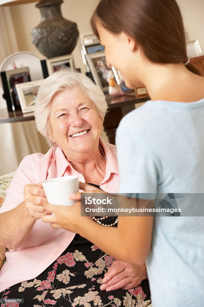 Adolescente fazendo avó neta bebida quente em casa - Foto de stock de 70 anos royalty-free