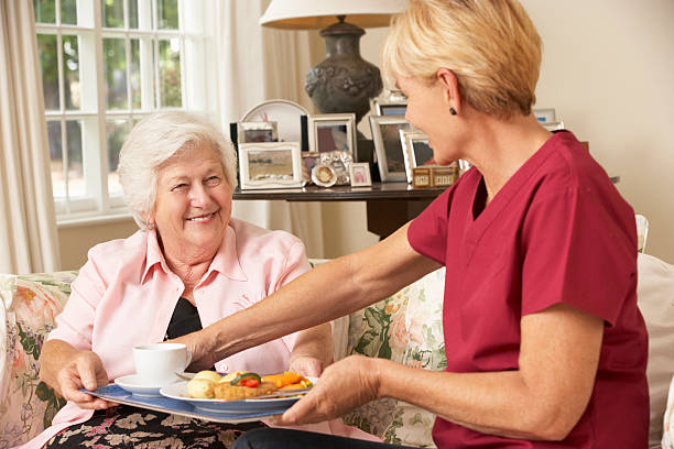 assistente de servir mulher idosa com cuidado refeição em casa - senior adult nursing home eating home interior imagens e fotografias de stock