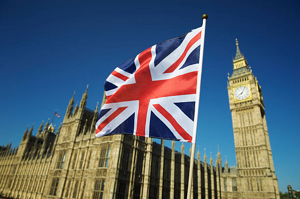 Union Jack British Flag Flies at Houses of Parliament London Union Jack British flag flies in bright blue sky at Houses of Parliament and Big Ben London british flag photos stock pictures, royalty-free photos & images