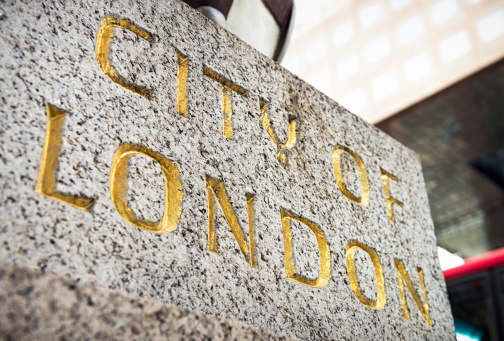 Close-up on the gilded words 'City Of London', cut into stone.