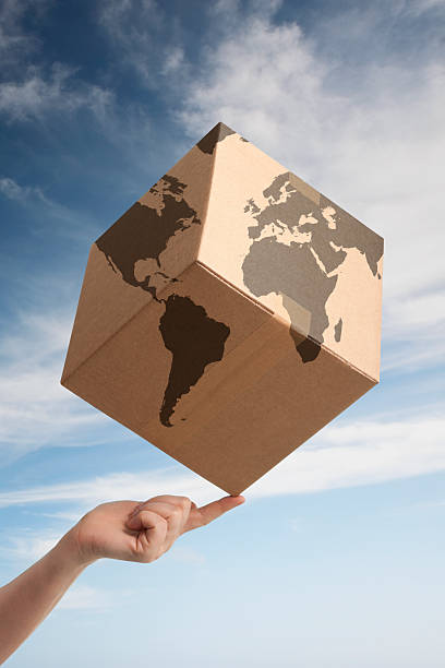 Balancing worldwide trade cardboard box and world map stock photo