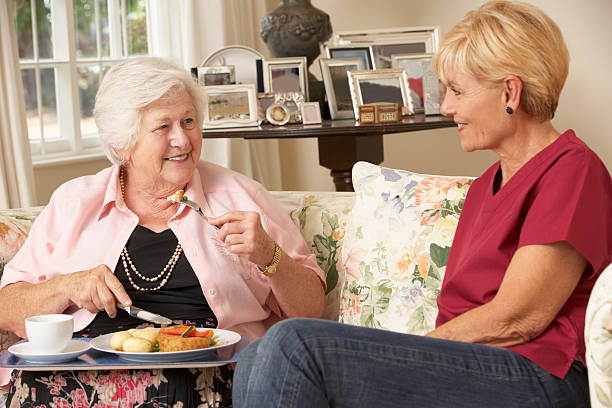 船の助手、お食事をお出しする老人女性自宅でケア - senior adult nursing home eating home interior ストックフォトと画像