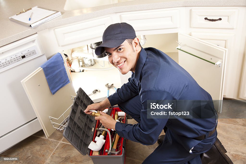 Latino plombier travaillant sous un évier, réparateur, la cuisine. Secteur des services. - Photo de Plombier libre de droits