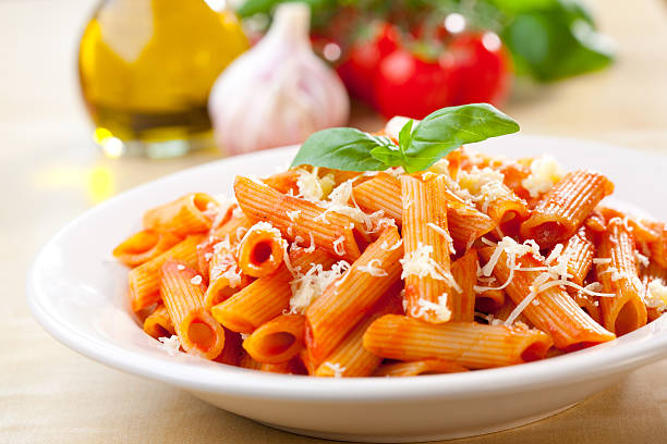 Penne, tomato and basil Plate of penne  with ingredients in the background. penne stock pictures, royalty-free photos & images