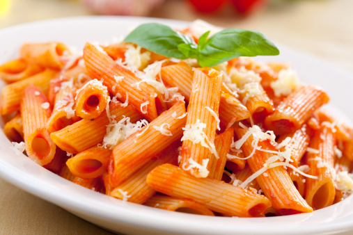 Plate of penne  with ingredients in the background.