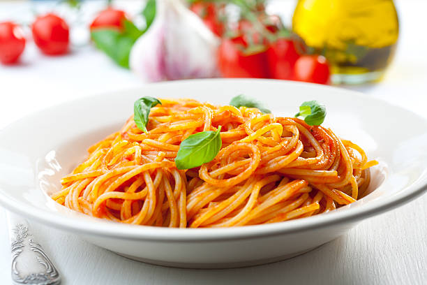 Spaghetti, tomato and basil Plate of penne  with ingredients in the background. tomato sauce stock pictures, royalty-free photos & images