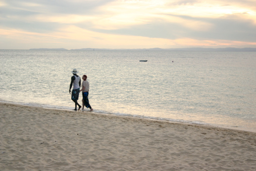 A young man and woman walking together on the beach at dusk. Photographed SE Queensland, Australia.