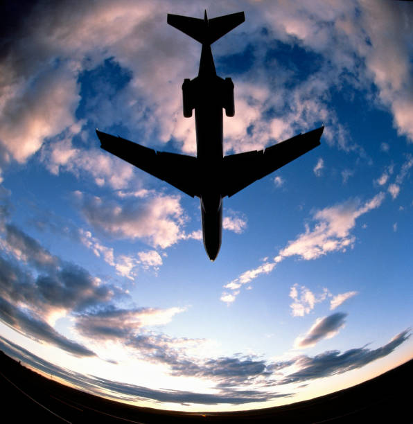 Fish-eye view of a Passenger Jetliner landing into the setting sun with a moody evening sky