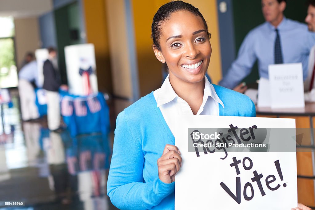 Giovane donna con la registrazione per accedere al centro di voto voto - Foto stock royalty-free di Iscrizione nelle liste elettorali